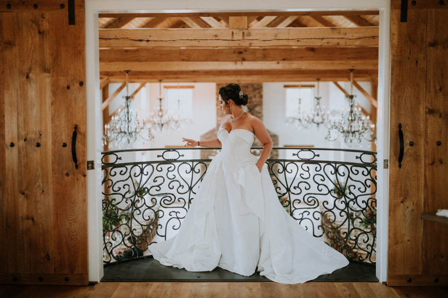 A bride standing at a magnificent iron balcony at a luxurious Virginia wedding venue.